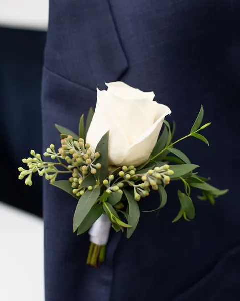 Prendedor de rosa blanca en traje azul