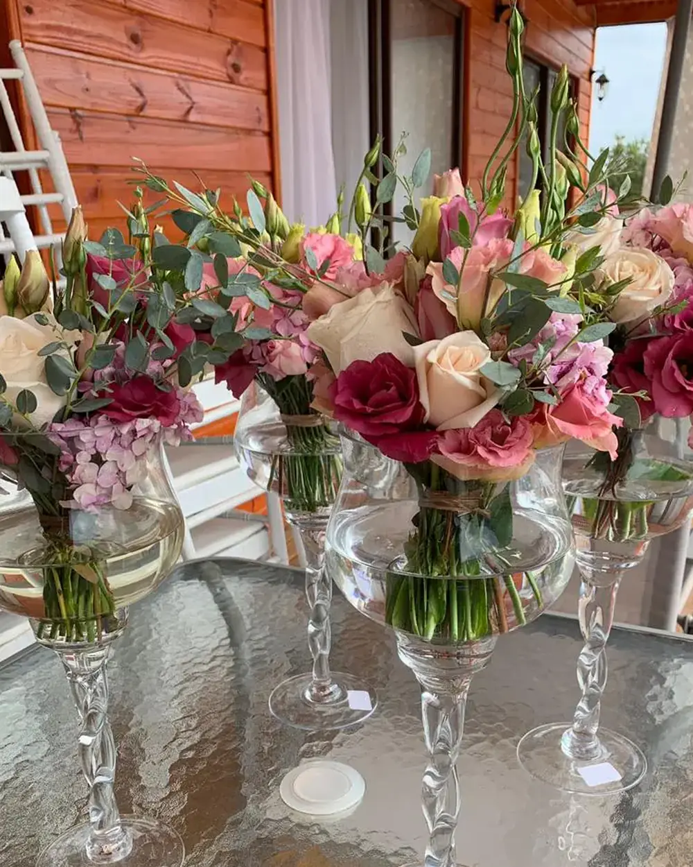 Centros de mesa con rosas y flores mixtas en copas de cristal