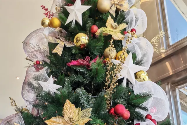 Estrellas blancas, flores doradas y malla en un árbol de Navidad