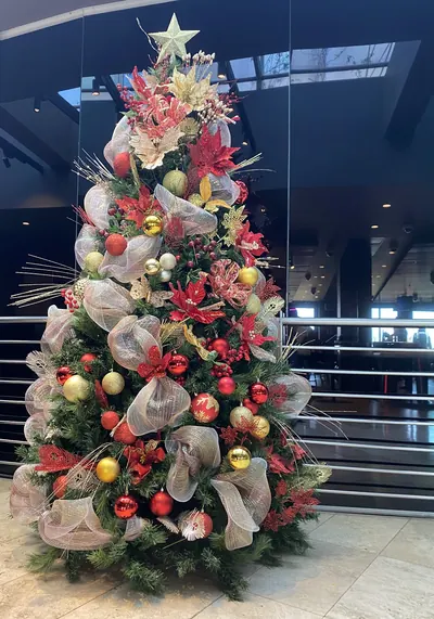 Árbol de Navidad con malla champaña, flores de pascua rojas y esferas doradas