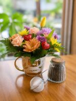 Taza con flores pastel, chocolates, frasco de té e infusor metálico