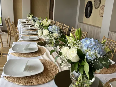 Mesa larga con centros bajos de rosas blancas e hortensias celestes, montaje de Encactus