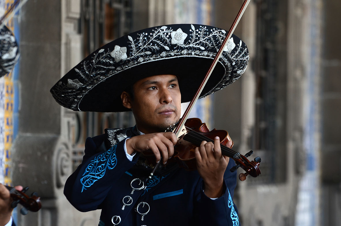 Mariachi con sombrero de charro tocando viol&iacute;n en una serenata